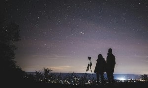 Two people using telescopes looking at a starry sky.