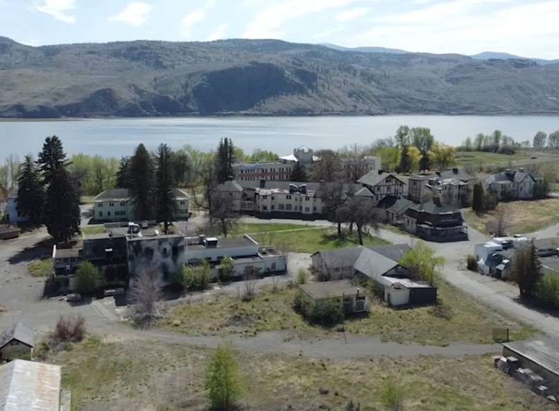 iN VIDEO: A chilling look at Kamloops’ historic Tranquille Sanitorium | iNFOnews.ca A cluster of buildings off all shapes and sizes sit on flat land among scattered trees with a lake in the background.