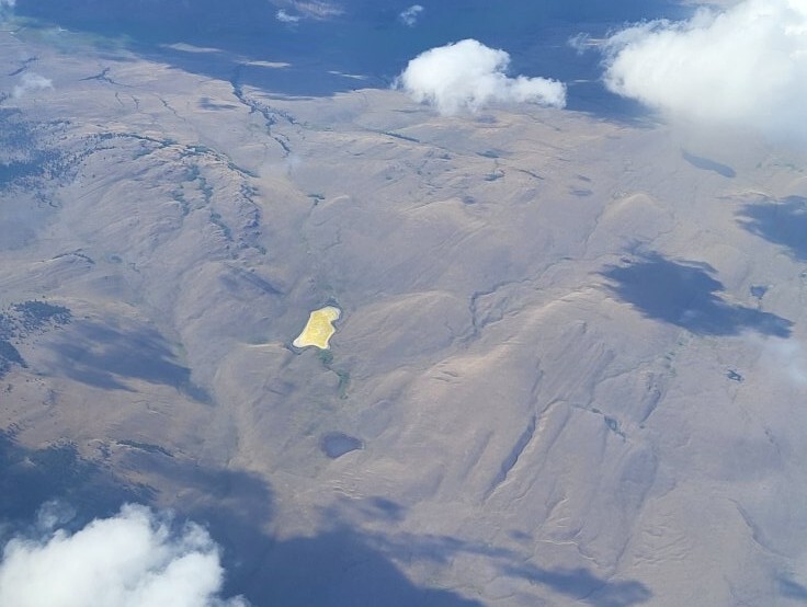 Why a lake spotted on flight to Kelowna is bright yellow | iNFOnews.ca A yellow lake in far off mountains is pictured from the window of a commercial plane.